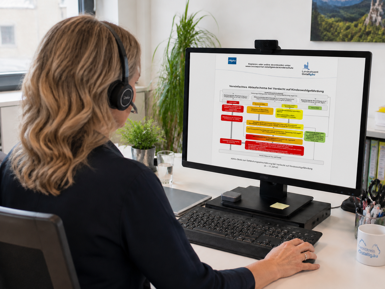 Eine Person mit Kopfhörern sitzt an einem Schreibtisch und schaut auf einen Computerbildschirm, auf dem ein Flussdiagramm angezeigt wird. Der Hintergrund zeigt einen modernen Arbeitsplatz mit Pflanzen und Fenstern.