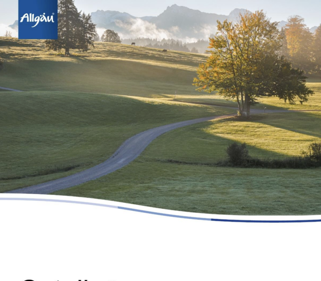 Eine malerische Landschaft im Allgäu zeigt sanfte Hügel, einen geschwungenen Weg und einen Holzstall. Bäume umranden die Szene, und im Hintergrund sind Berge und Nebel sichtbar. Der frühe Morgen sorgt für eine ruhige, friedliche Atmosphäre.