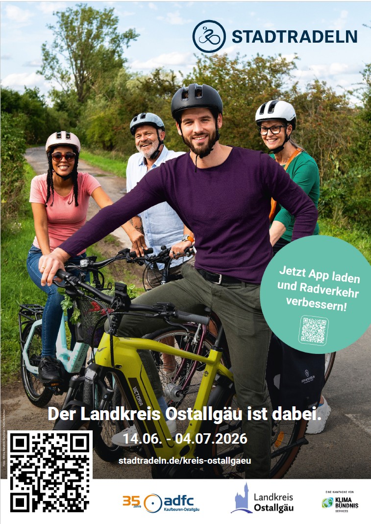Eine Gruppe von vier Radfahrern steht auf einem Radweg, lächelnd und in freizeitlicher Kleidung. Im Hintergrund sind Bäume zu sehen. Der Text informiert über eine Radaktionswoche im Landkreis Ostallgäu von 14.06. bis 04.07.2026.